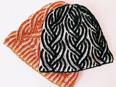 two black and orange hats sitting next to each other on top of a white surface