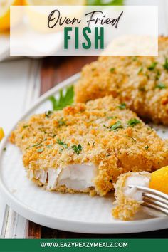 a white plate topped with fried fish next to lemons and garnished with parsley