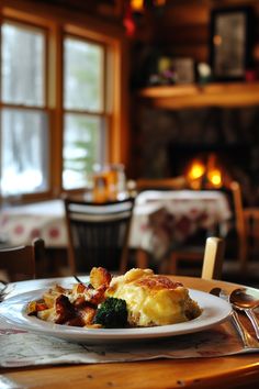 a white plate topped with food on top of a wooden table next to a window