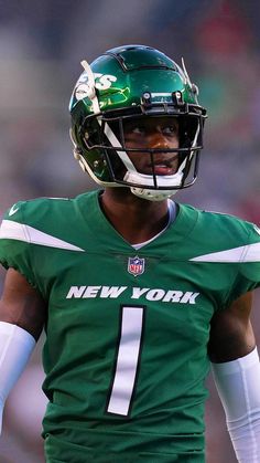 a close up of a football player wearing a green uniform and holding a ball in his hand