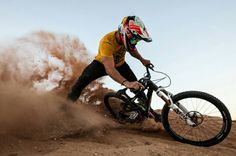 a man riding a mountain bike on top of a dirt covered slope in the desert