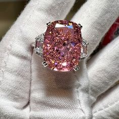 a pink diamond ring sitting on top of a white glove