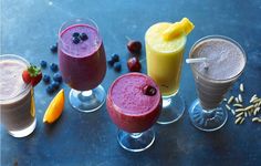 four glasses filled with different types of smoothies