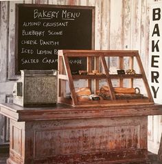 an old bakery display with bread and pastries on the counter in front of a chalkboard