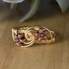 "Handmade Tiny Copper Tone Flower Beads, Sterling Silver, Yellow or Rose Gold Filled Wire Wrapped Ring; Custom Made to Size *This tiny copper tone metal flower beads and wire wrapped ring is handmade with two approximately 6mm in diameter metal flower beads and your choice of wire band. *This ring (as well as all the others in my shop) is custom made to any size from 4 to 14 including half and quarter sizes! *This ring can be made in Sterling Silver Filled Wire, Argentium Sterling Silver wire (t Adjustable Copper Flower Jewelry, Witches Alphabet, Copper Flowers, Diy Wire Jewelry Rings, Wire Jewelry Patterns, Wire Jewelry Rings, Wire Wrap Jewelry Designs, Wire Wrapped Jewelry Diy, Wire Wrapped Jewelry Tutorials