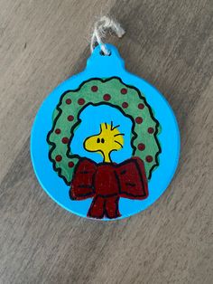 a blue ornament with a cartoon giraffe holding a wreath on it