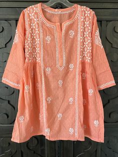 Women's Coral Color Pure Cotton Kurti Lucknowi Hand Embroidered Top at PinkPhulkari California Bohemian Straight Kurta Tops For Navratri, Casual Festive Kurta With Intricate Embroidery, Festive Tunic Tops For Navratri, Cotton Cutdana Tops, Traditional Embroidered Straight Kurta Top For Summer, Cotton Anarkali Tunic Kurta, Cotton Resham Embroidery Straight Kurta Top, Cotton Anarkali Style Kurta Tunic, Cotton Anarkali Style Tunic Kurta