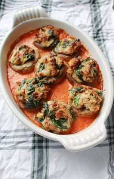 a casserole dish filled with stuffed mushrooms and tomato sauce on a checkered table cloth