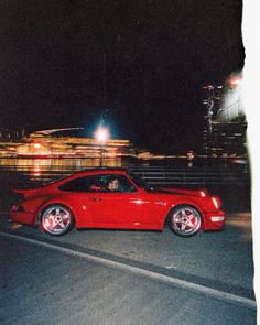 a red car driving down the road at night