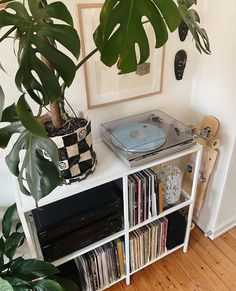 a record player sitting on top of a white shelf next to a potted plant