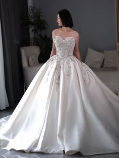 a woman in a white wedding dress is walking down the runway with her back to the camera