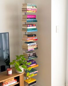 a tall stack of books sitting on top of a wooden table next to a tv