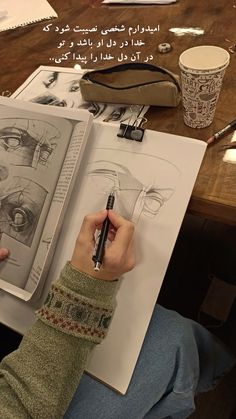 a person is holding a pen in their hand and looking at an open book with drawings on it