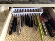 kitchen utensils are organized in a drawer under the counter top, including knives and spatulas