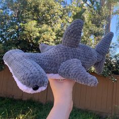 a hand holding up a stuffed toy shark