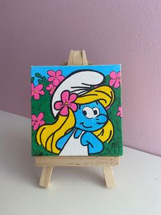 an easel with a painting of a cartoon character on it's side and pink flowers in the background