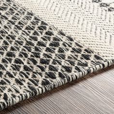 an animal print rug on top of a wooden floor next to a white and black area rug