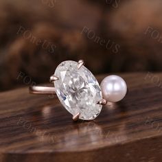 an oval shaped diamond and pearl ring on top of a wooden table