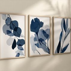 three framed art pieces hanging on the wall in front of a white wall with blue flowers