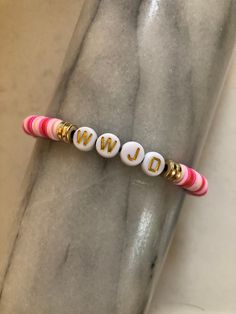 two white and pink beads with the word wd on them are sitting in front of a marble slab