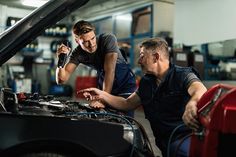 two mechanics working on an engine in a garage