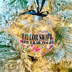 taylor swift the eras tour ornament hanging on a christmas tree with snowflakes