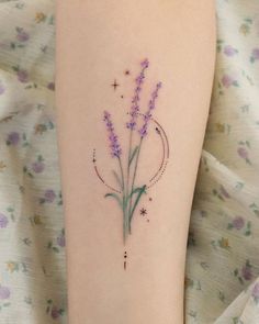 a small tattoo on the leg of a woman's arm with flowers and stars