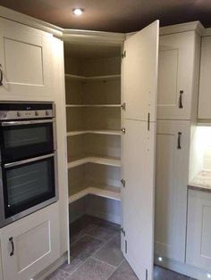 an empty kitchen with two ovens and white cupboards in the corner between them