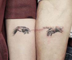 two people with matching tattoos on their arms touching each other's hands and holding the same object