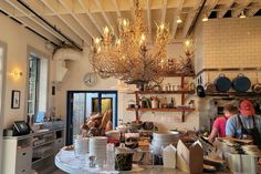 two men working in a kitchen with lots of clutter on the counter and hanging chandelier