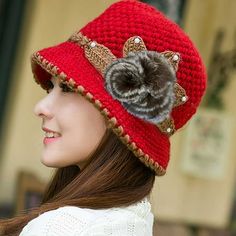 a woman wearing a red crocheted hat with a flower on the front and side