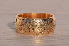 The Chartres: Antique Hand Engraved Band in Yellow Gold. Exuding timeless elegance, this antique yellow gold band boasts a generous width of 8.9mm, adorned with intricate hand-engraved scrolled and floral patterns. Crafted with meticulous attention to detail, the band showcases the artistry of its 14 karat yellow gold composition. Currently sized at 9.75, it can be delicately adjusted to achieve a perfect fit for an additional charge upon request. Love this piece, but don't have the money to spe Luxury Etched Heirloom Bands, Luxury Yellow Gold Engraved Ring In Recycled Material, Luxury Antique Gold Bracelet Engraved, Ornate Gold Engraved Ring For Ceremonial Occasions, Ornate Gold Engraved Ring With Intricate Design, Traditional Gold Engraved Ring With Decorative Band, Traditional Etched Yellow Gold Engraved Ring, Traditional Engraved Ring With Intricate Design For Formal Occasions, Traditional Yellow Gold Engraved Ring