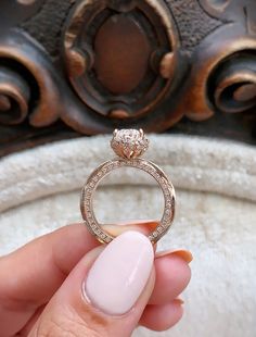 a hand holding a diamond ring in front of a mirror