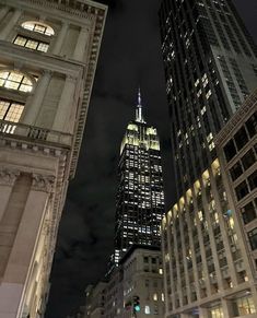 the empire building is lit up at night in new york city, ny on an overcast day