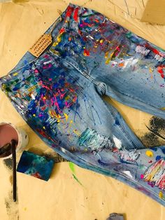 a pair of blue jeans with paint splattered all over them