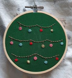 a cross stitch christmas tree ornament hanging from a hoop