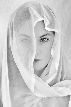 black and white photograph of a woman wearing a veil over her head, looking directly into the camera