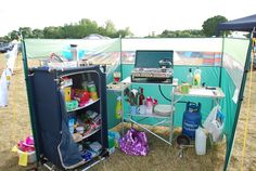 an outdoor kitchen is set up in the middle of a field with other camping equipment