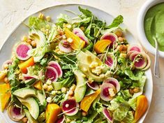 a salad with radishes, avocado and chickpeas is served on a white plate