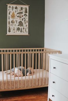 a baby laying in a crib next to a dresser