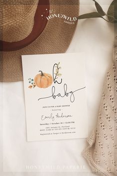 a baby announcement card with a pumpkin and leaves on it next to a straw hat