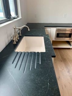 a kitchen with black counter tops and white sink in the center, next to a window