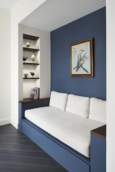 a blue and white living room with a couch in the corner next to a book shelf