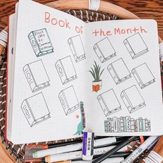 an open notebook with the words book of the month written on it next to crayons and markers