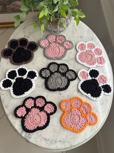 a marble table topped with lots of crocheted animal paw coasters on top of it