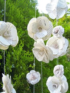 some paper flowers hanging from strings outside