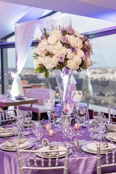 the table is set with purple linens and white flowers