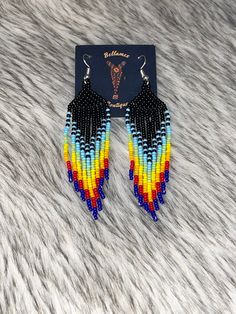 the multicolored beaded earrings are on top of a fur surface with a black tag