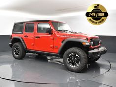 a red jeep is parked in a room with a black and white wall behind it