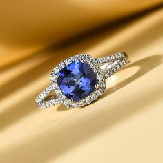 a tan and white gold ring with a blue stone surrounded by diamonds on a yellow background